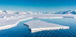 arktis sommerlandskap på Svalbard. Islagt fjord omkranset av snødekte fjell. Det er en stor råk i isen  og et isflak flyter midt i råken