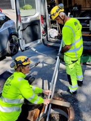 To personer i signalfargede verneklær er på vei ned i en kum. Foto: Ruden AS