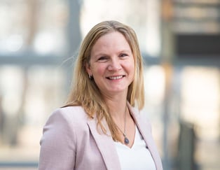 Portrett av dame med lyst, halvlangt hå som smiler mot kamera