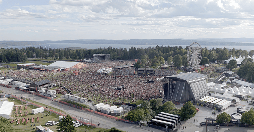 oversikt over festivalområde, tett med mennesker, fjord i bakgrunnnen