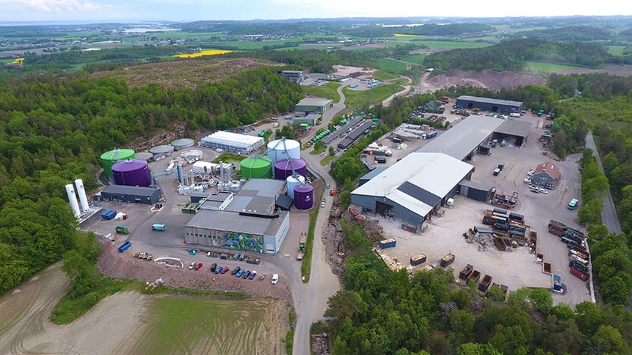 Oversiktsbilde over et stort industriområde med mange bygg og grønn natur rundt.