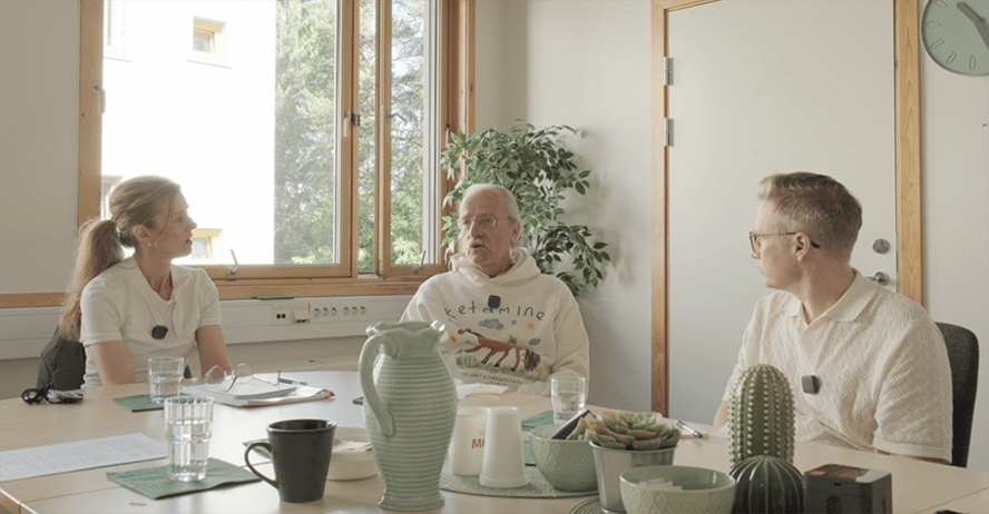 to menn og en kvinne som diskuterer rundt eg bord