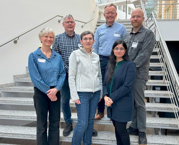 Bildet viser fem middelaldrende mennesker stående i en trapp i Forskningsrådets lokaler.