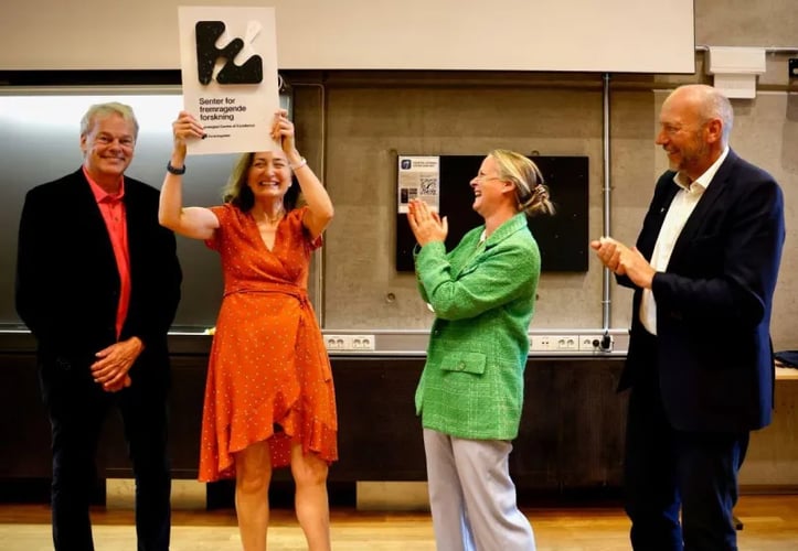 Direktør i Forskningsrådet - Mari Sundli Tveit - feirer statusen som senter for Fremragende Forskning sammen med nobelprisvinnerne Moser. May Britt Moser holder en plakett der det står SFF over hodet.