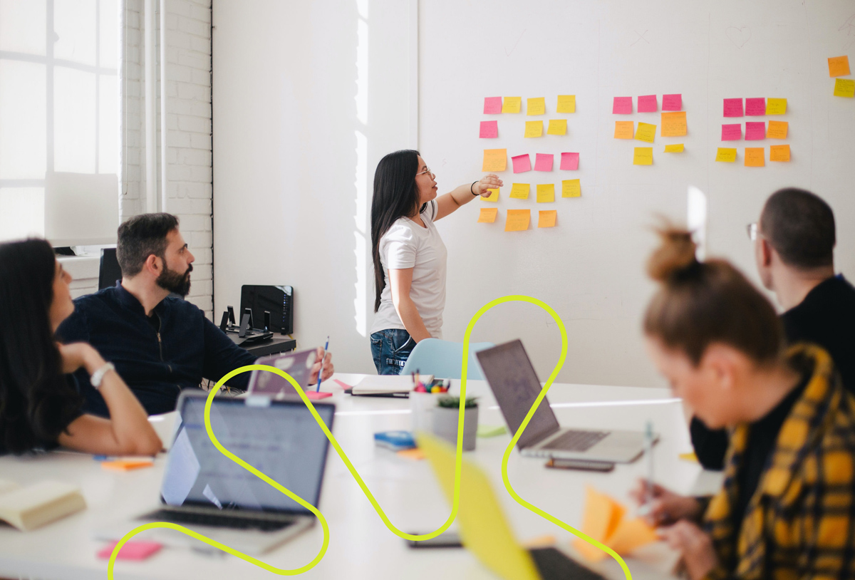 Fem personer som samarbeider og bruker post-it lapper